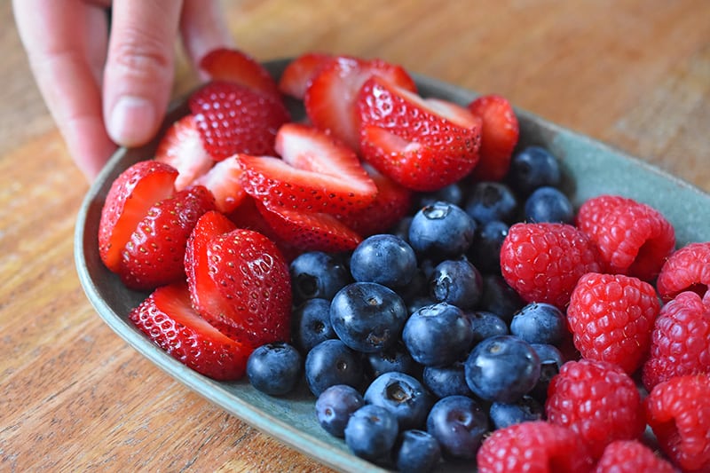 A closeup view of a plate filled with strawberries, blueberries, and raspberries.