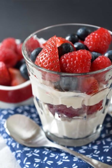 A side view of a clear glass filled with Paleo Vanilla Pudding Parfait with strawberries and blueberries