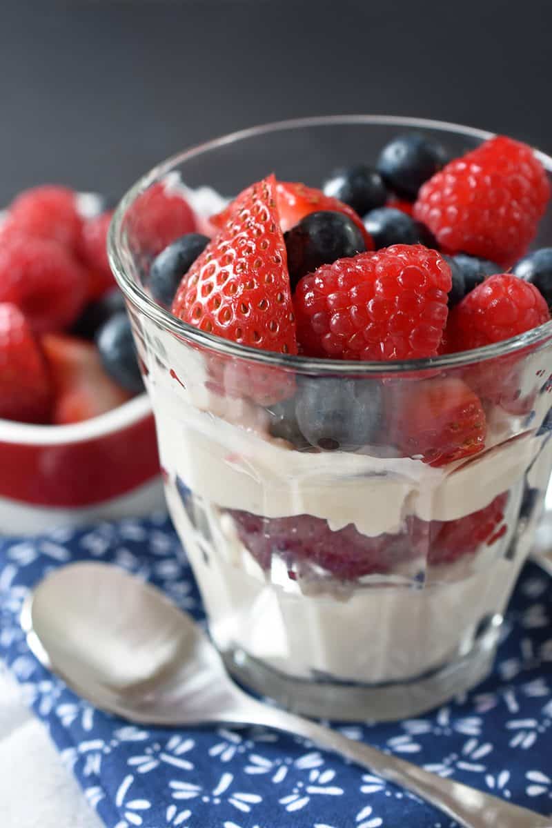 A closeup view of a cup of paleo vanilla pudding parfait with strawberries and blueberries.