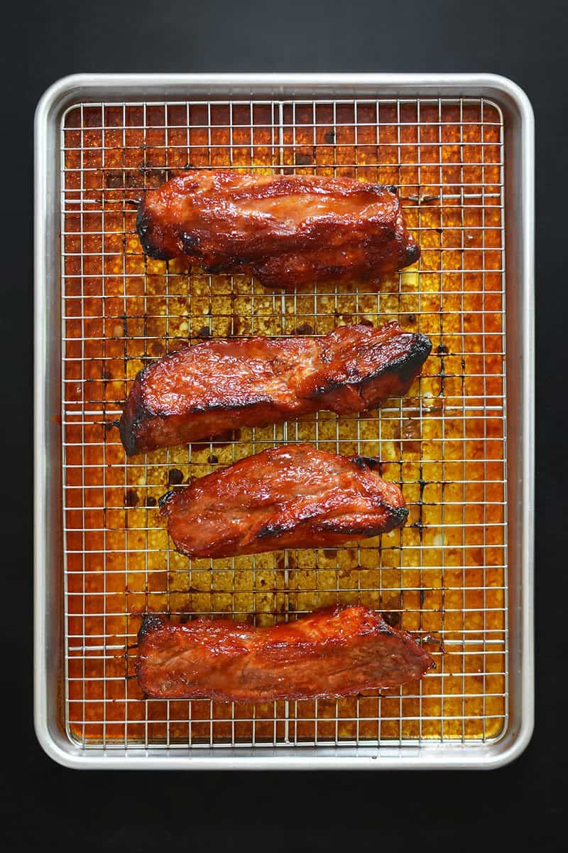 An overhead shot of Paleo Char Siu (Chinese BBQ Pork) on a rimmed baking sheet and wire rack, right out of the oven.