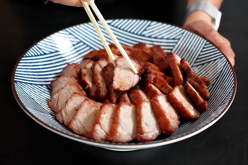 Pieces of Paleo Char Siu (Chinese BBQ Pork) arranged in a spiral in a blender and white Japanese serving bowl.
