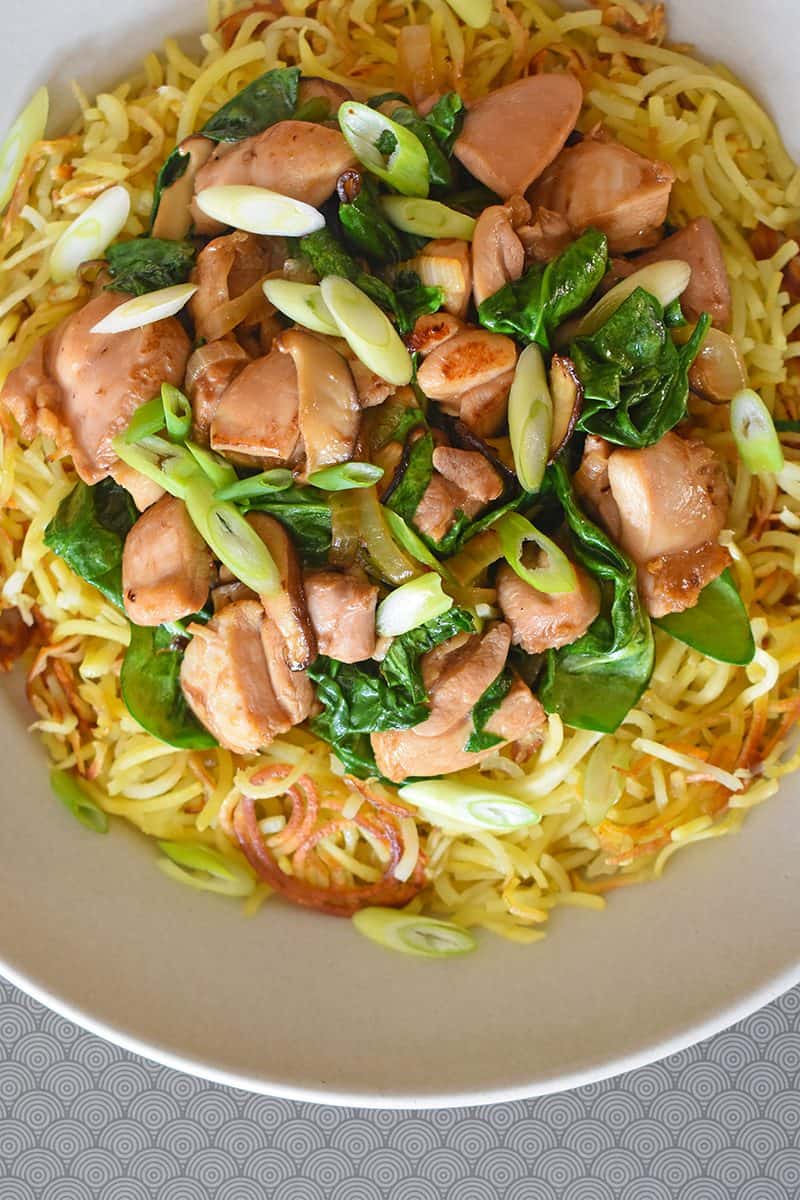 An overhead shot of a white platter topped with Paleo Chicken Chow Mein, a Whole30 recipe that uses spiralized sweet potatoes in place of wheat noodles.