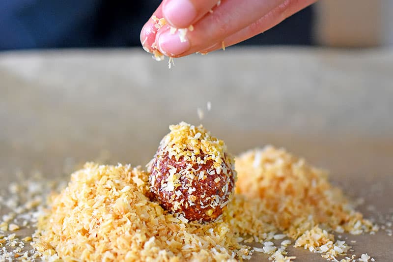Tossing “PB&J” Energy Balls into toasted shredded coconut.
