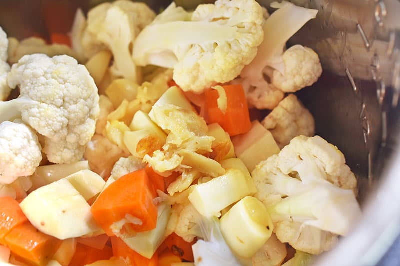 An instant pot containing parsnips, carrots, and cauliflower.