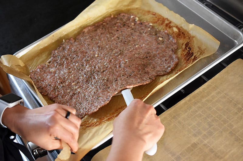 Transferring the cooked sausage crust to a clean piece of parchment paper.