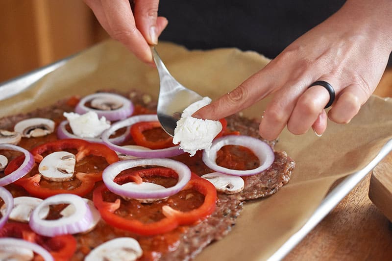 Dolloping dairy-free nut cheese on the meatza.