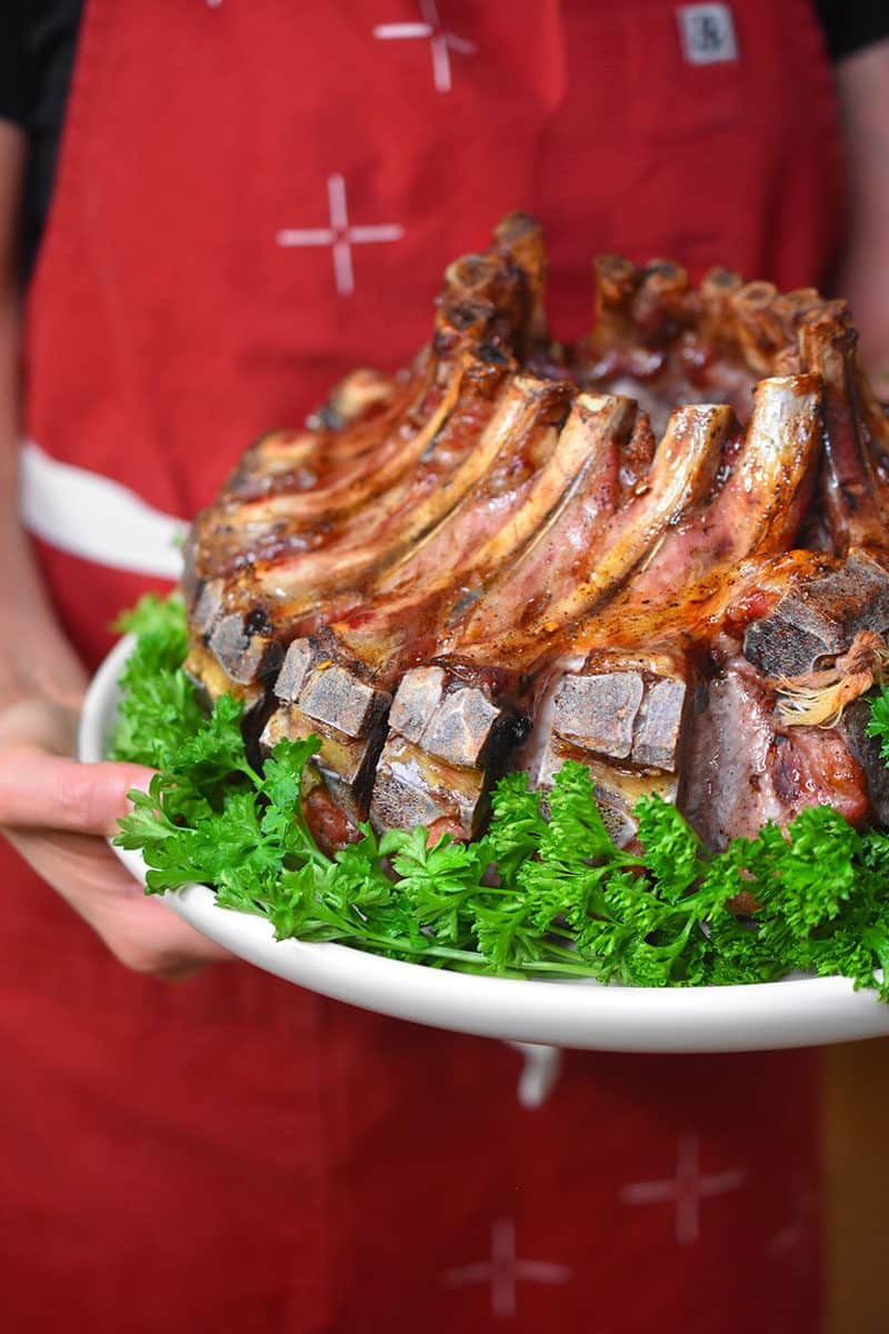 A close up of someone holding a plate of magic crown roast of pork.
