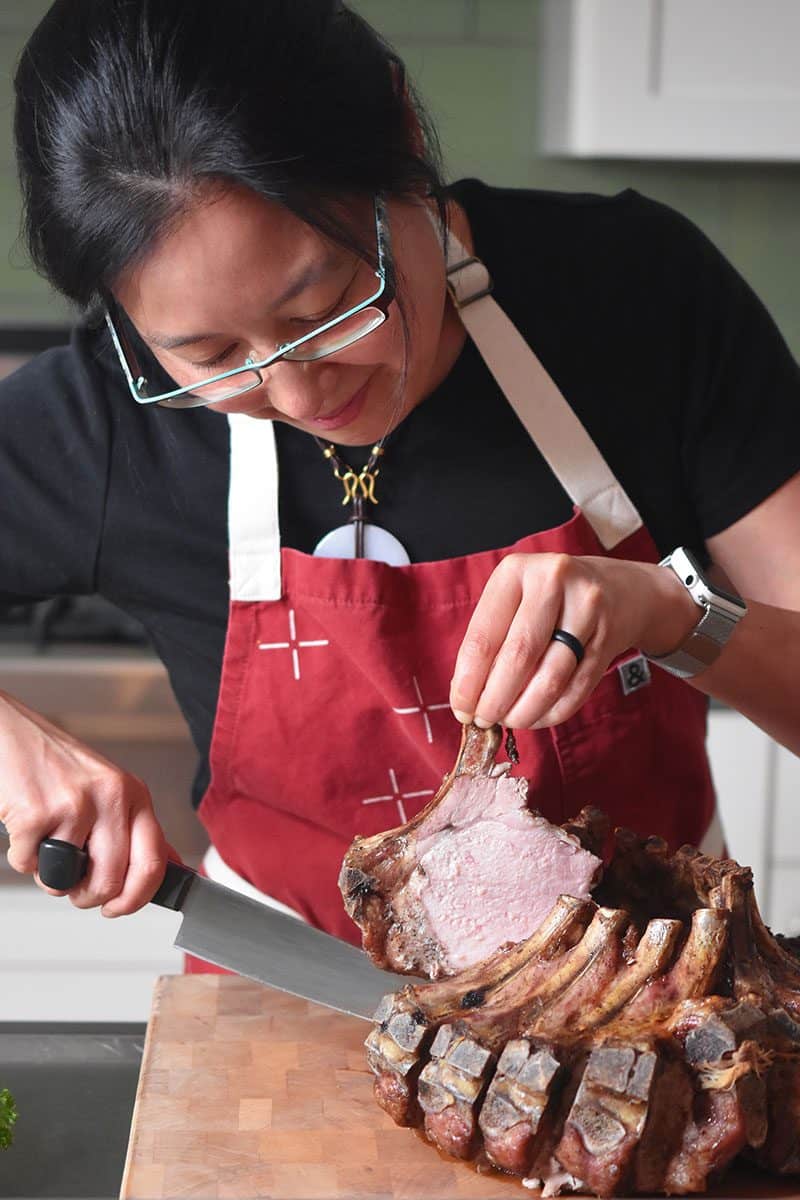 Someone slicing off piece of the Magic Crown Roast of Pork.