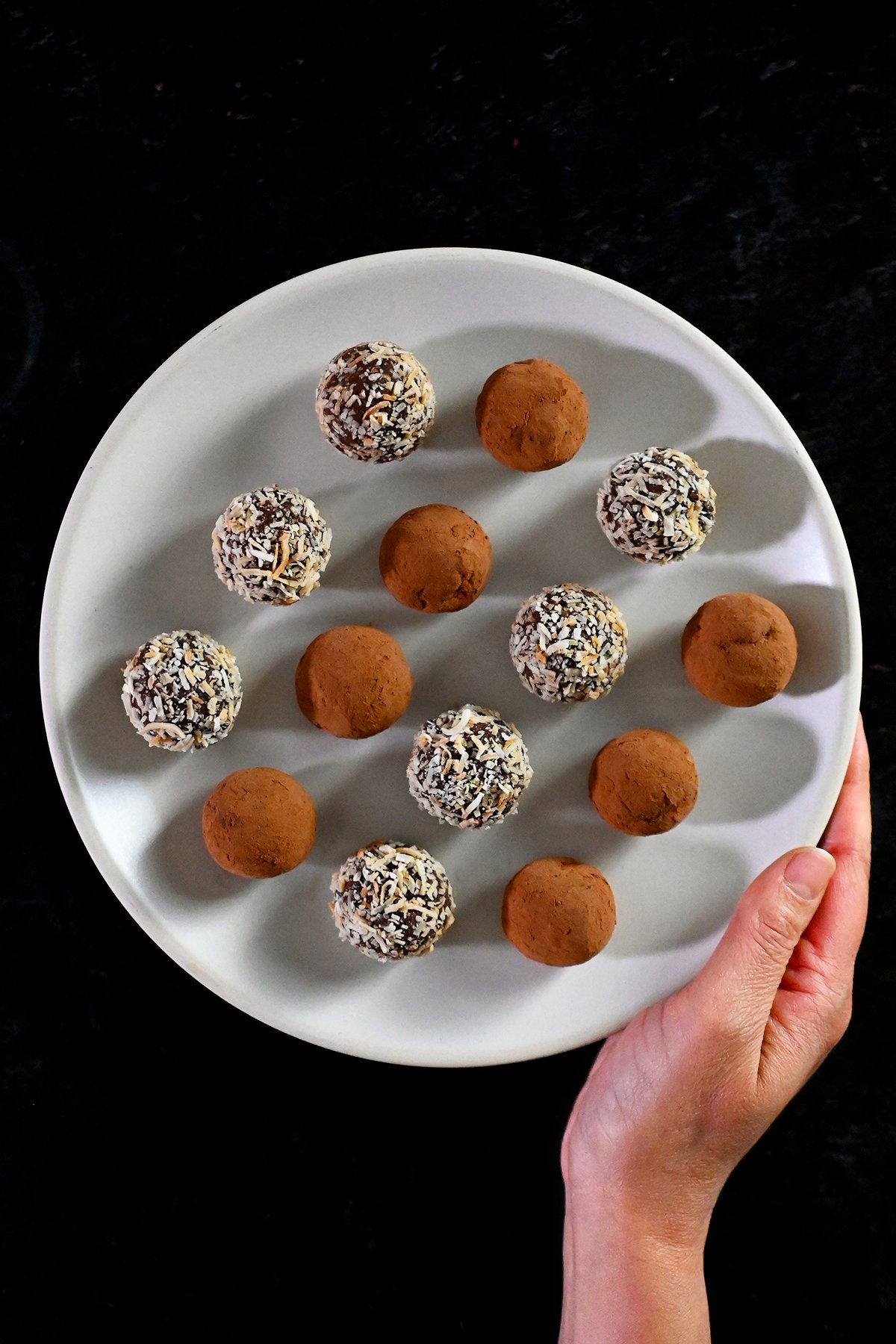 A closeup of two Nom Nom Paleo Chocolate Truffles covered with toasted shredded coconut