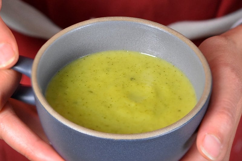 A blue coffee mug filled with paleo Curried Cream of Broccoli Soup 