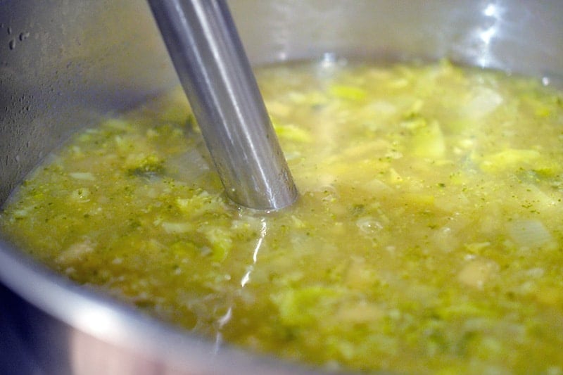 An immersion blender in a pot of Whole30 Curried Cream of Broccoli Soup 