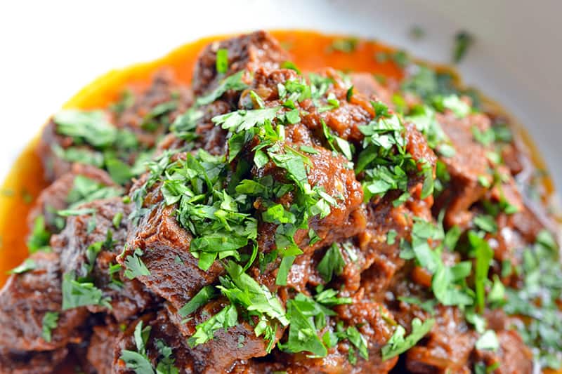 Oven-Braised Mexican Beef in a dish topped with parsley.