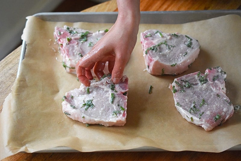 Placing pork chops in a single layer on a rimmed baking sheet