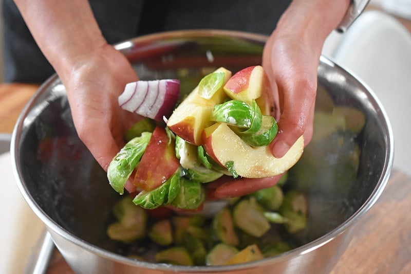 Tossing the apples, onions, and Brussels sprouts in the marinade.