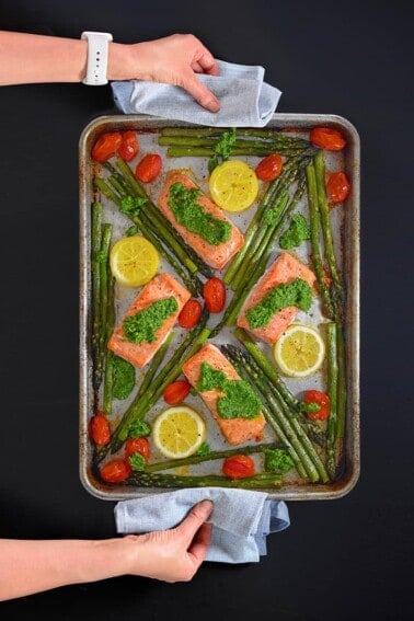An overhead shot of a sheet pan salmon supper with asparagus and pesto.
