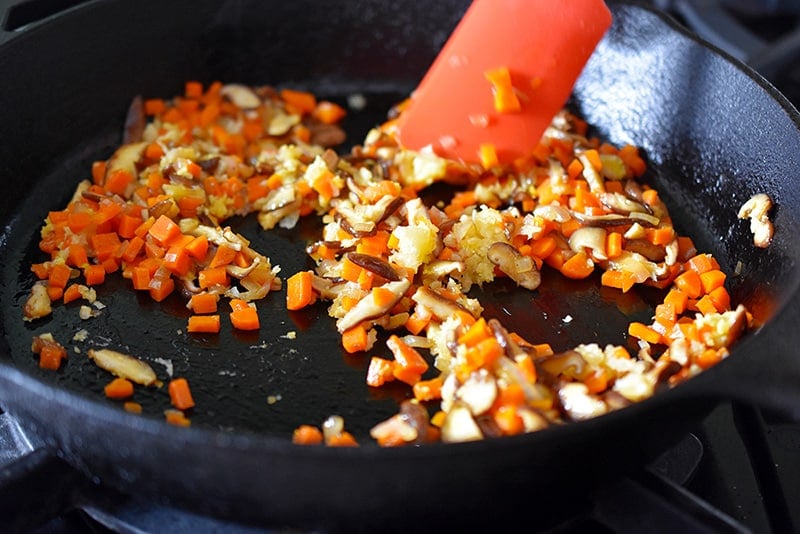 Adding minced garlic and ginger to a pan.