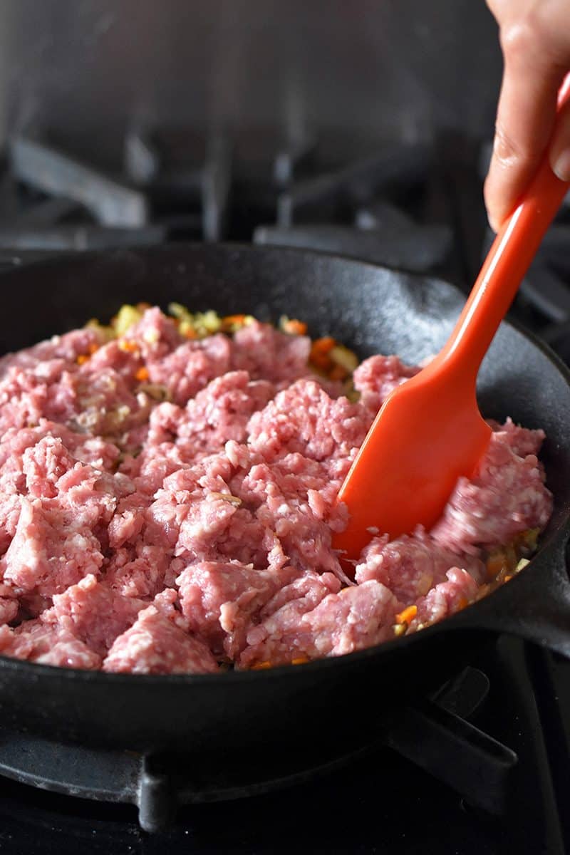 Stirring ground pork in the pan of egg roll in a bowl. 