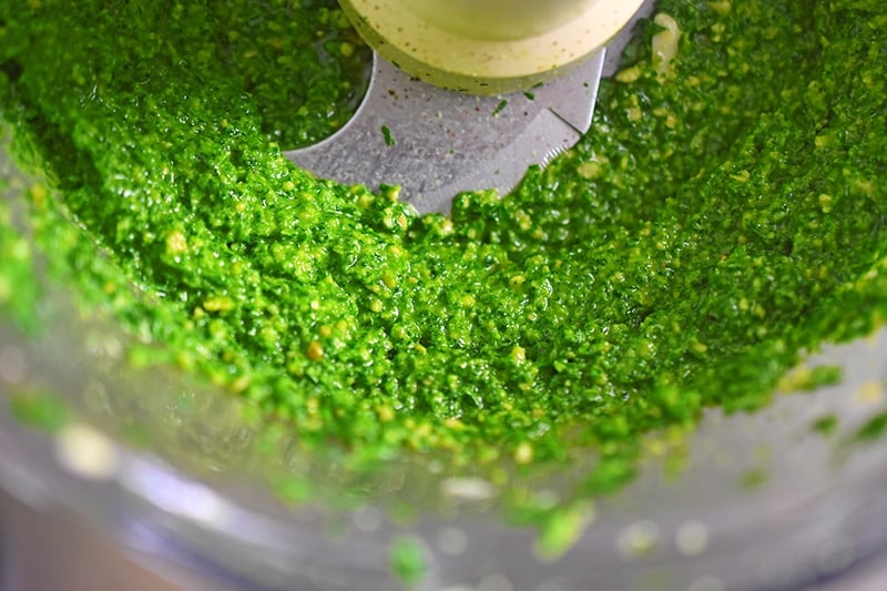 An overhead shot of the pesto in a food processor mixed together.