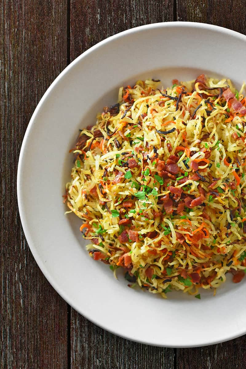 A white bowl filled with Crispy Swoodles (sweet potato noodles) and bacon. 