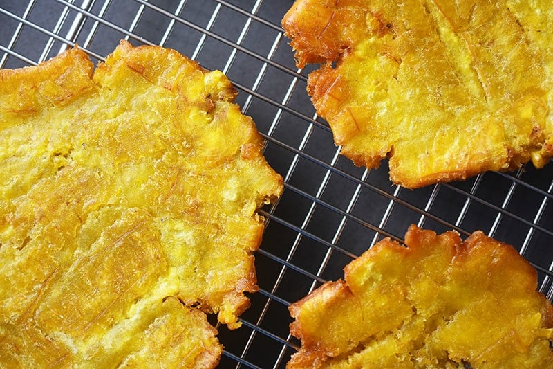 Overhead shot of the fried green plantains on a wire rack for the paleo and Whole30 recipe of fried green plantains and mango avocado salsa.