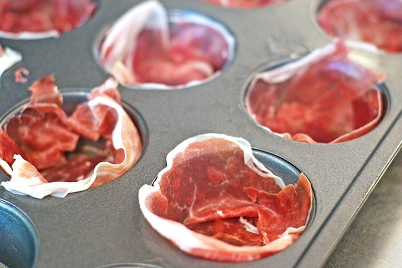 A muffin tin is lined with prosciutto for the egg muffins.