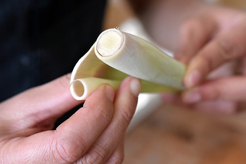 Peeling off the tough outer layer on a lemongrass stalk.