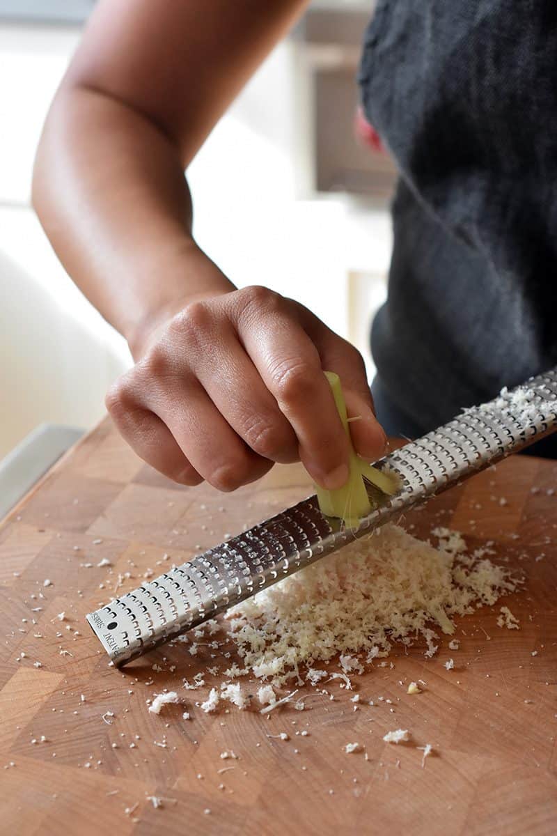Using a microplane rasp grater to mince a trimmed piece of lemongrass.