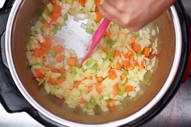 An overhead shot on an open Instant Pot with the mirepoix sautéing for the gravy.