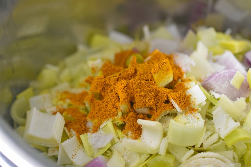 A closeup of the vegetables and curry seasoning in the Instant Pot to make dairy-free Curried Cream of Broccoli Soup 