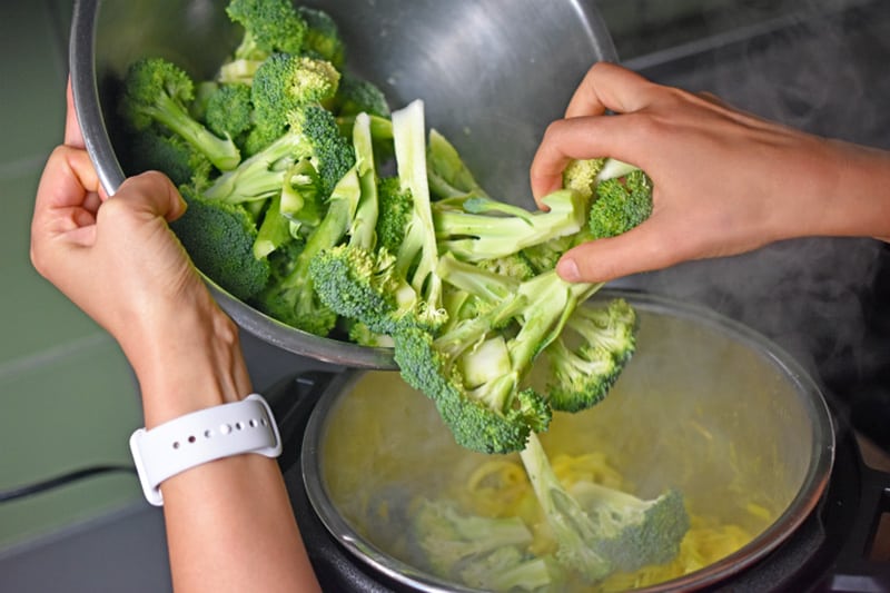 Adding chopped broccoli to an Instant Pot to make Curried Cream of Broccoli Soup 