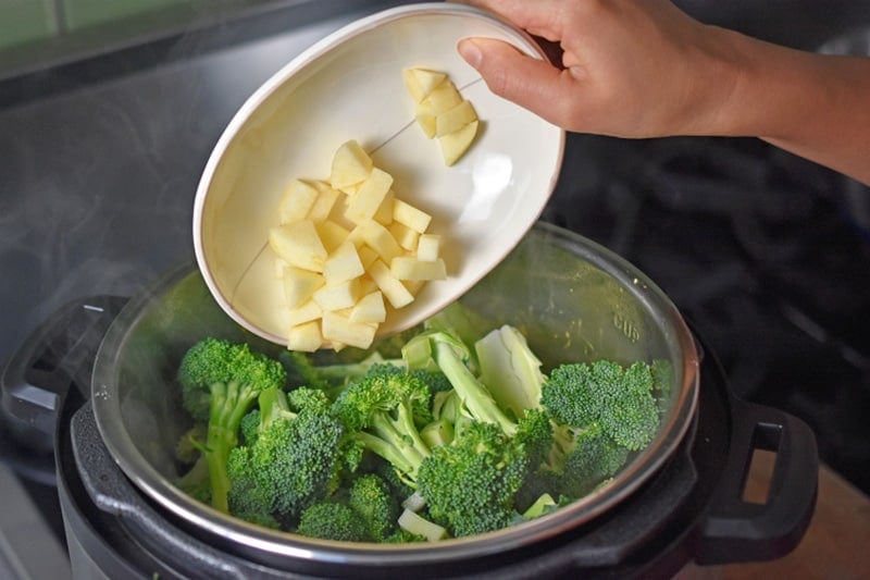 Adding diced apple to an Instant Pot to make Curried Cream of Broccoli Soup 