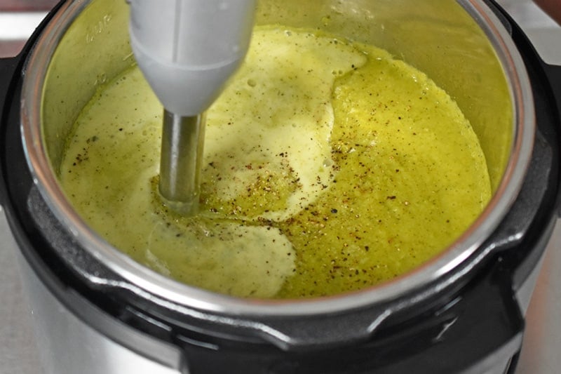 An immersion blender is mixing in the coconut milk into Instant Pot Curried Cream of Broccoli Soup 