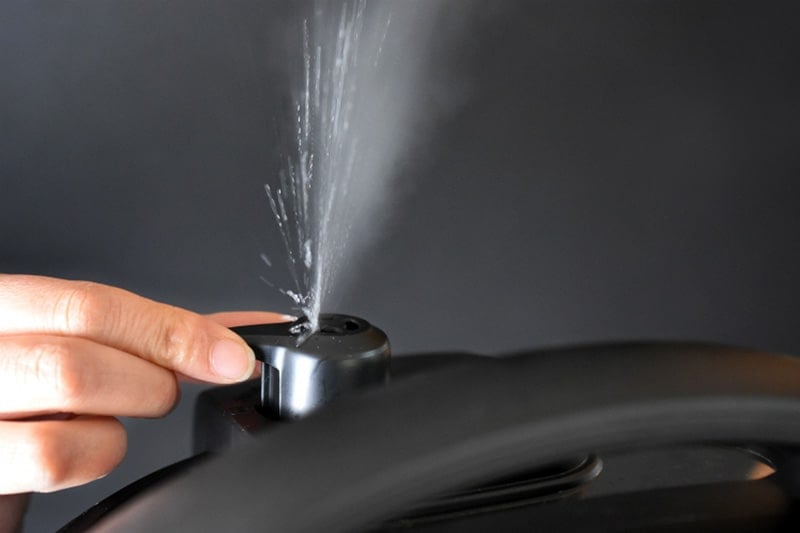 A close-up image of a hand manually releasing the pressure valve on an Instant Pot.