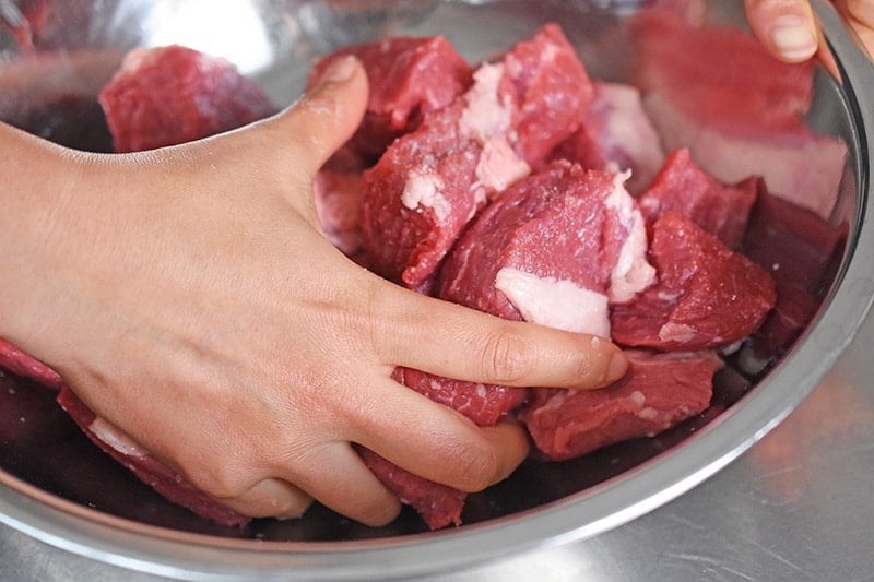 The beef and salt are tossed by hand to distribute the seasoning.