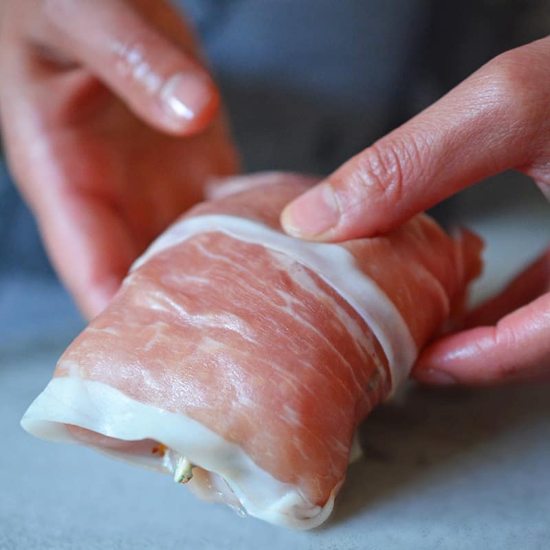 A shot of someone wrapping Chicken Prosciutto Involtini and getting it ready for the oven.