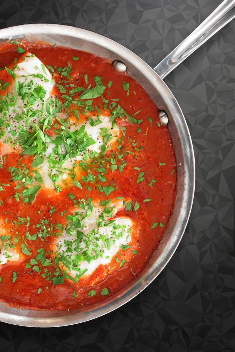 An overhead shot of Poached Cod in Tomato Sauce in a large stainless steel skillet, a simple Whole30 and keto weeknight dinner.