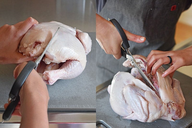 Cutting the back bone out of a raw chicken.