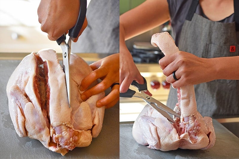 Cutting both sides of the backbone out of a raw whole chicken.