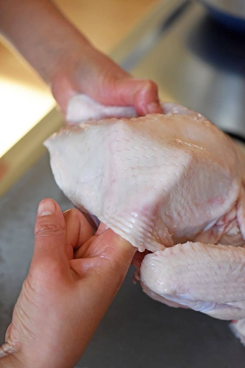 Sticking two fingers below the skin of the chicken to loosen it from the meat