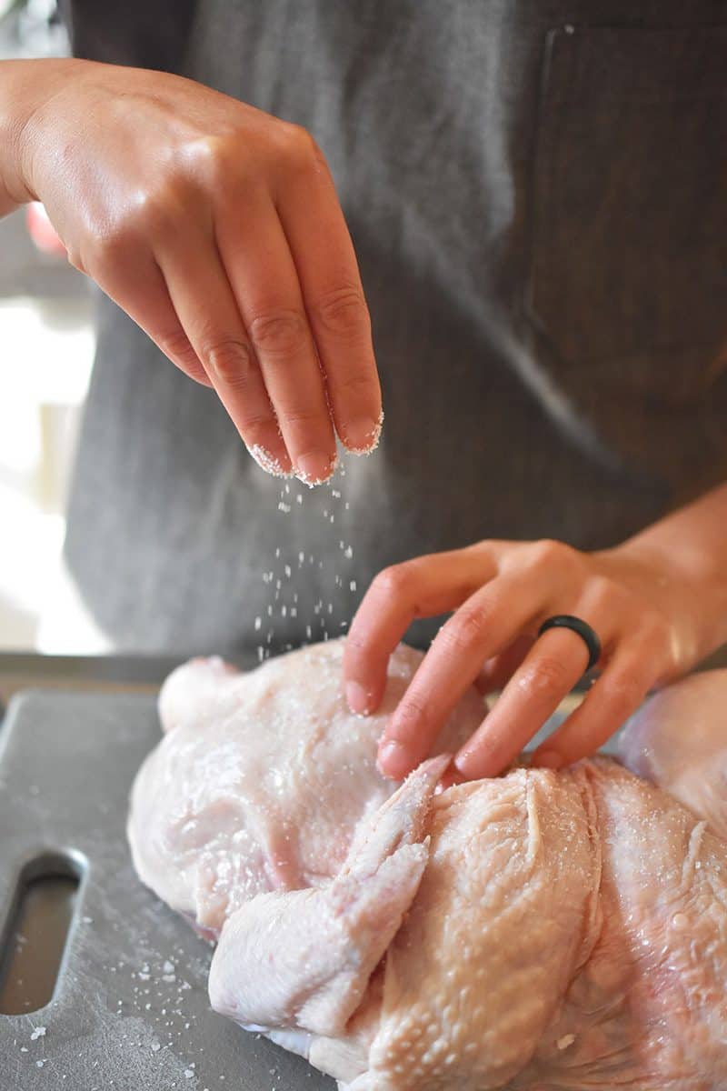 Sprinkling salt on top of the raw chicken skin.