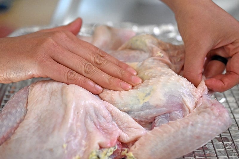 Massaging the herb butter under the skin to distribute it evenly all over the chicken.