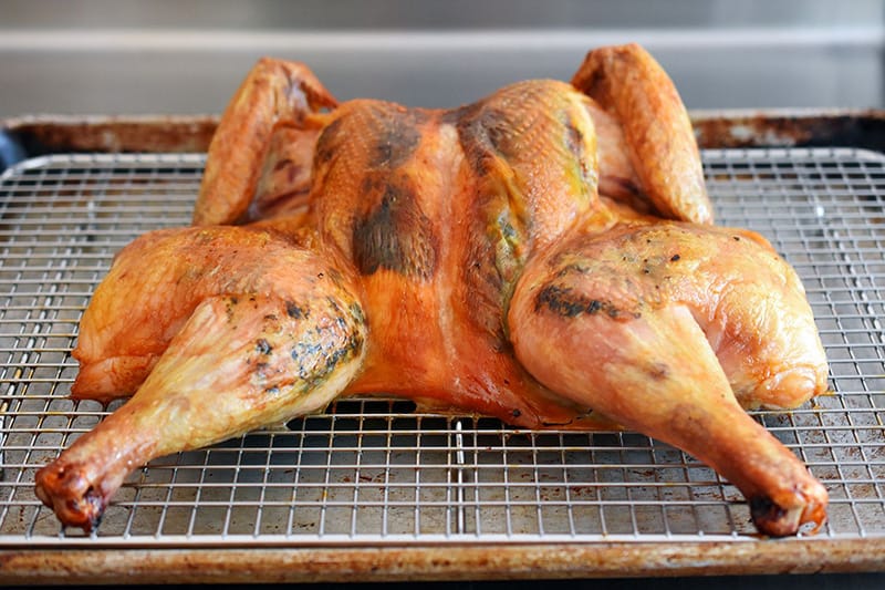 A Spatchcocked Chicken with Herb Butter resting on a wire rack.