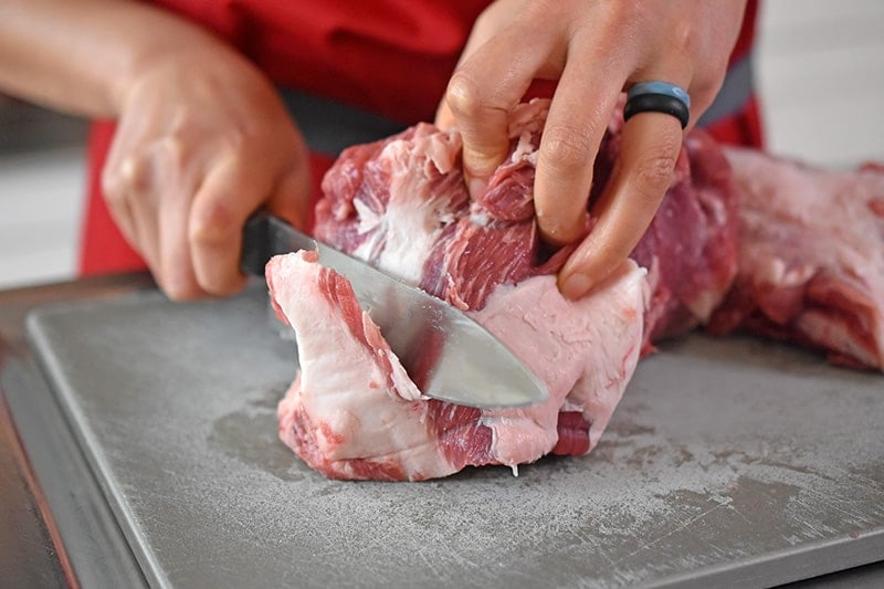 Trimming the fat off of a pork shoulder roast
