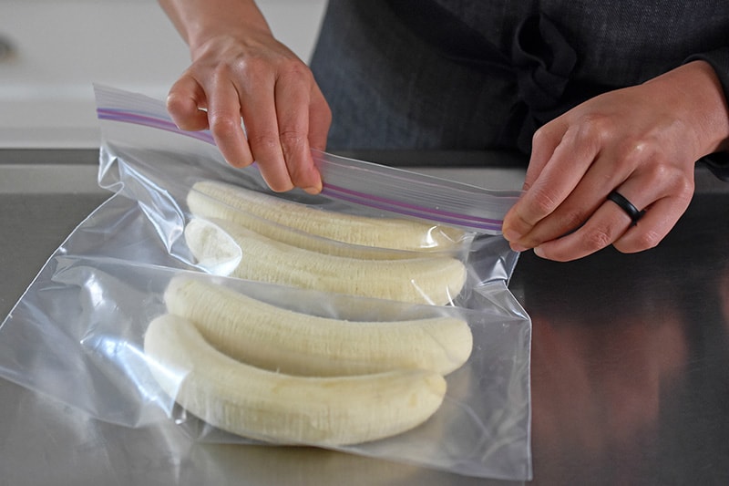 Four bananas are being sealed in a plastic bag.