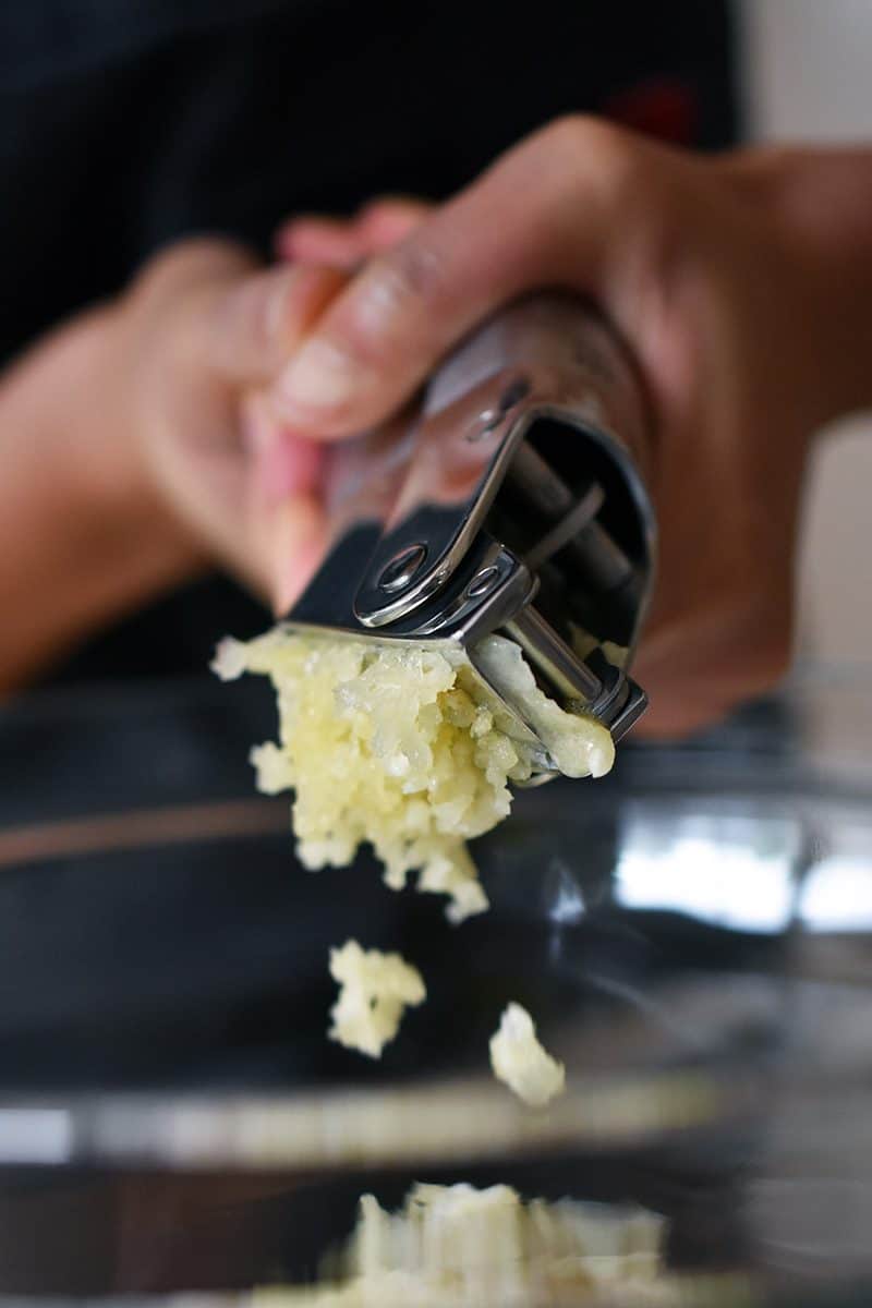 Adding minced garlic from a garlic press to the marinade for Vietnamese Lemongrass Chicken 