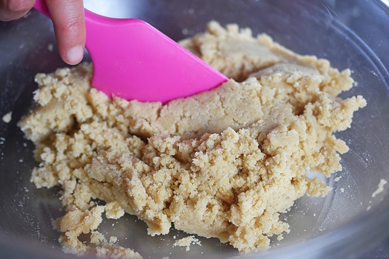 A closeup of a pink silicone spatula mixing cookie dough. 