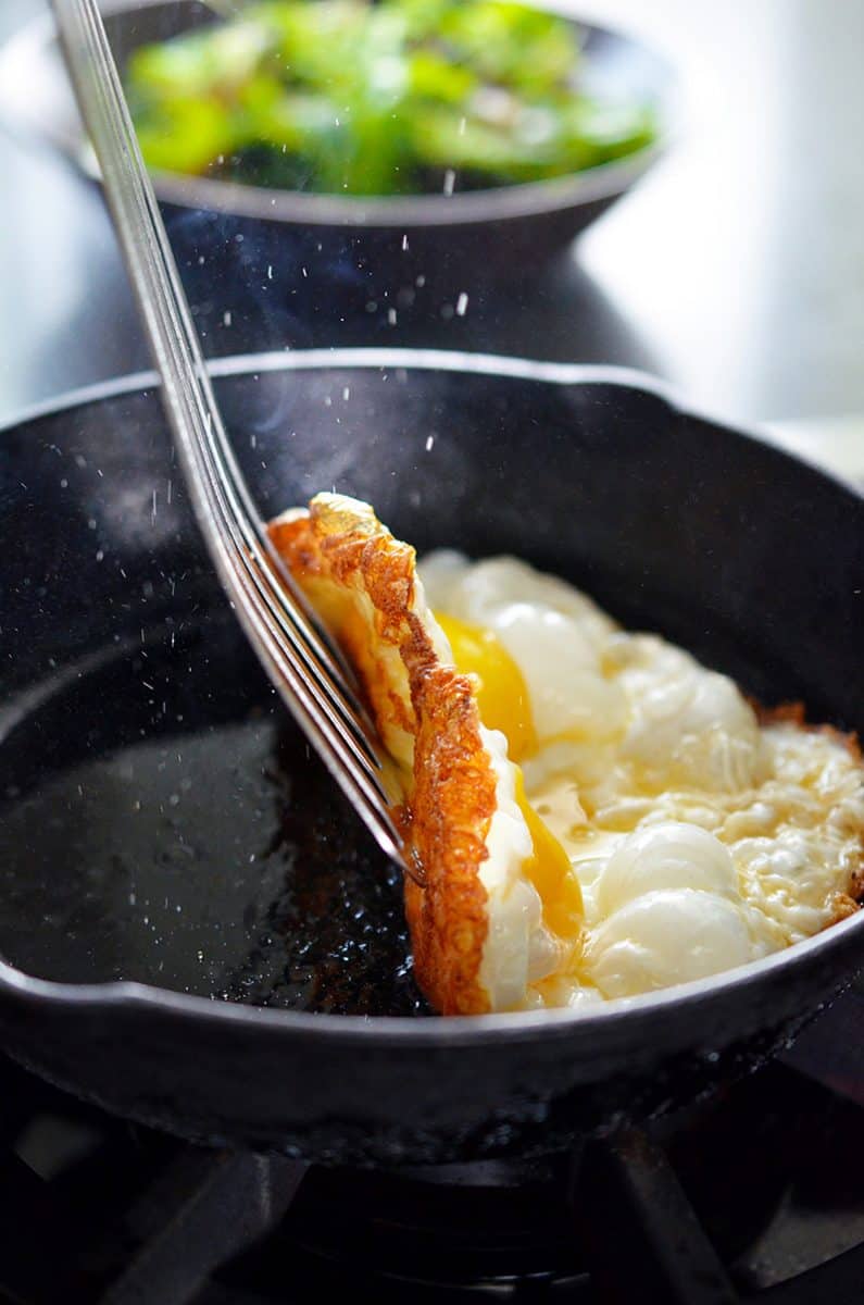 A thin spatula lifts up the crispy egg to expose the browned whites on the bottom. 