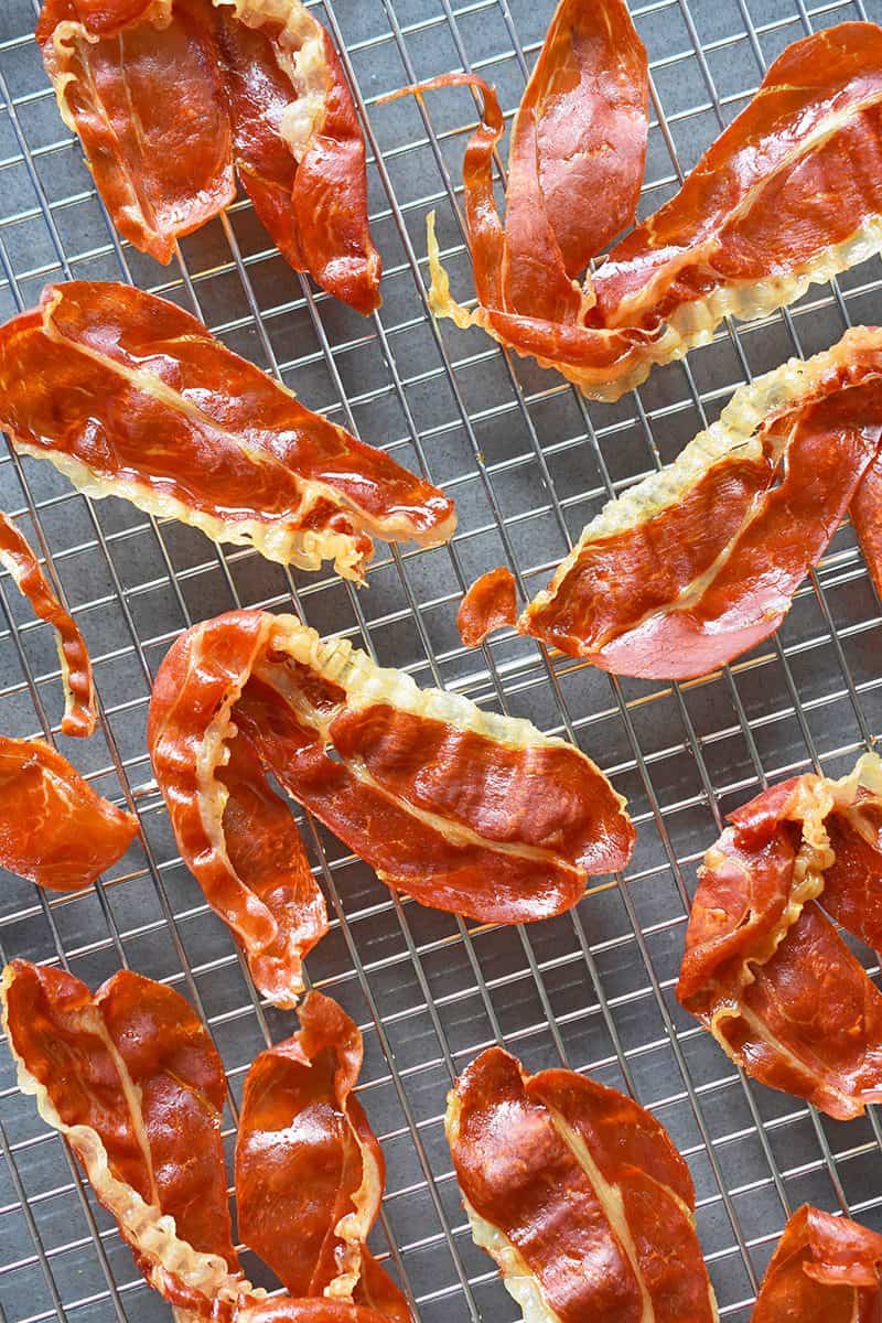 Crispy, baked slices of prosciutto on a wire rack.