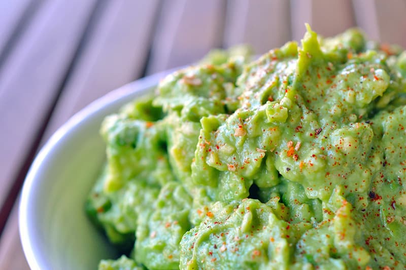 A large bowl of guacamole is shown sprinkled with Aleppo pepper on top.