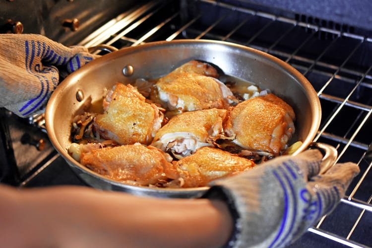 Placing the skillet of Cantonese Crispy Chicken Thighs into the oven.